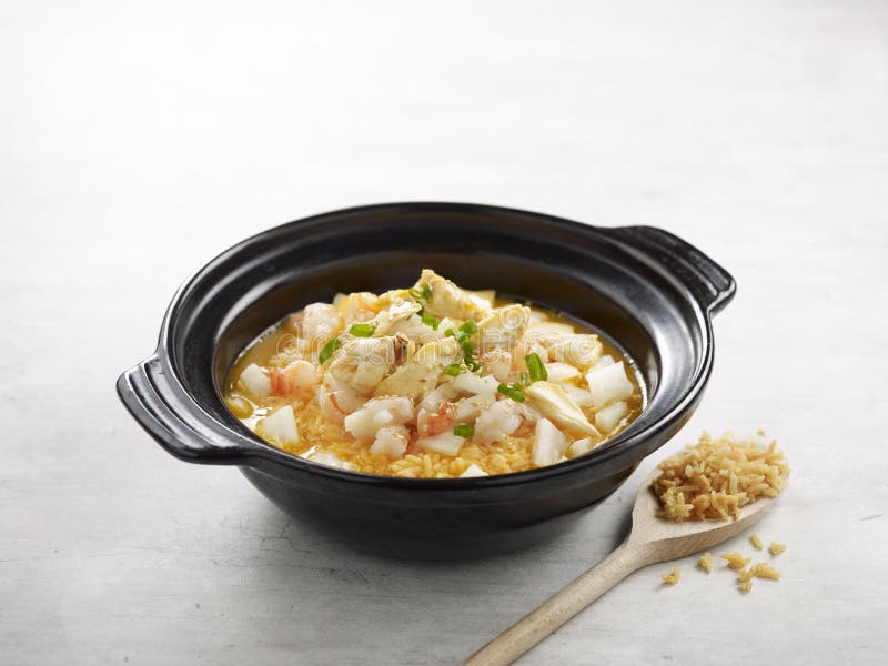 Poached Rice with Assorted Seafood in Lobster Broth served in a pot side view on grey background royalty free stock photography