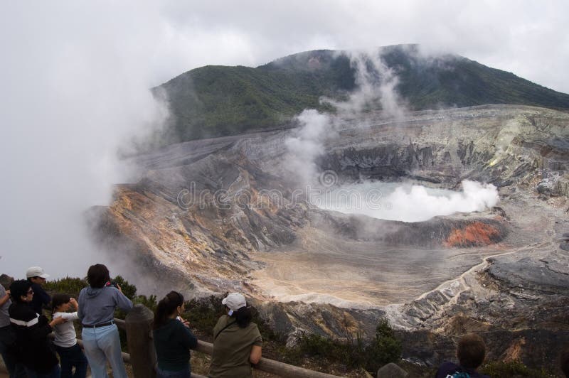 Aerial view of Poas Volcano. Group of tourists looking at its crater while smoke comes out