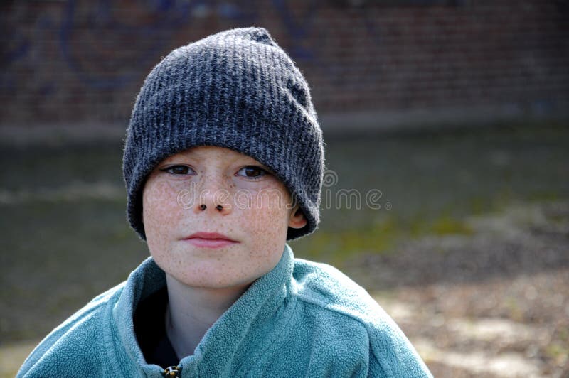 Portrait of a poor boy with knitted hat and much too big clothes,, hoping for a better life. Portrait of a poor boy with knitted hat and much too big clothes,, hoping for a better life