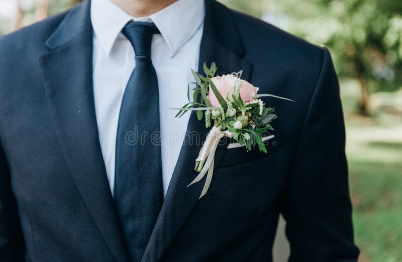 Bridegroom in a suit with a tie with a butanier flower in his jacket pocket. Bridegroom in a suit with a tie with a butanier flower in his jacket pocket