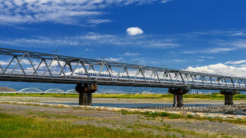 Shizuoka, Japan - May 05, 2017:  JR Tokaido Shinkansen train thundering on railway bridge with view of mountain fuji. Super high speed train N700 can transit between Tokyo and Osaka, architecture, asia, asian, background, beautiful, beauty, blue, bullet, east, fast, japanese, landmark, landscape, modern, mt, nature, outdoor, outdoors, railroad, river, scene, scenery, sky, snow, station, structure, summer, technology, tourism, transport, transportation, travel, urban, volcano, white, winter, yokohama. Shizuoka, Japan - May 05, 2017:  JR Tokaido Shinkansen train thundering on railway bridge with view of mountain fuji. Super high speed train N700 can transit between Tokyo and Osaka, architecture, asia, asian, background, beautiful, beauty, blue, bullet, east, fast, japanese, landmark, landscape, modern, mt, nature, outdoor, outdoors, railroad, river, scene, scenery, sky, snow, station, structure, summer, technology, tourism, transport, transportation, travel, urban, volcano, white, winter, yokohama