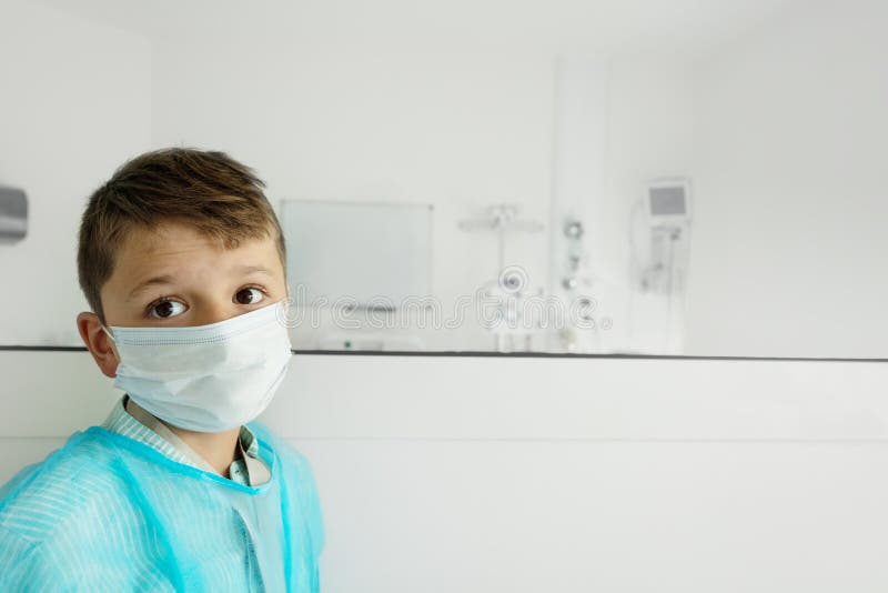 Little worried boy in medical mask near operations room in hospital. Little worried boy in medical mask near operations room in hospital