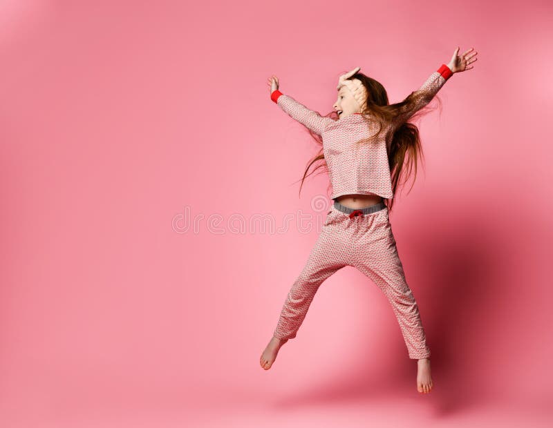 Poco muchacha pelirroja en el salto lindo de los pijamas y de los vendajes del pelo fotografía de archivo Poco muchacha pelirroja en el salto lindo de los pijamas y de los vendajes del pelo fotografía de archivo