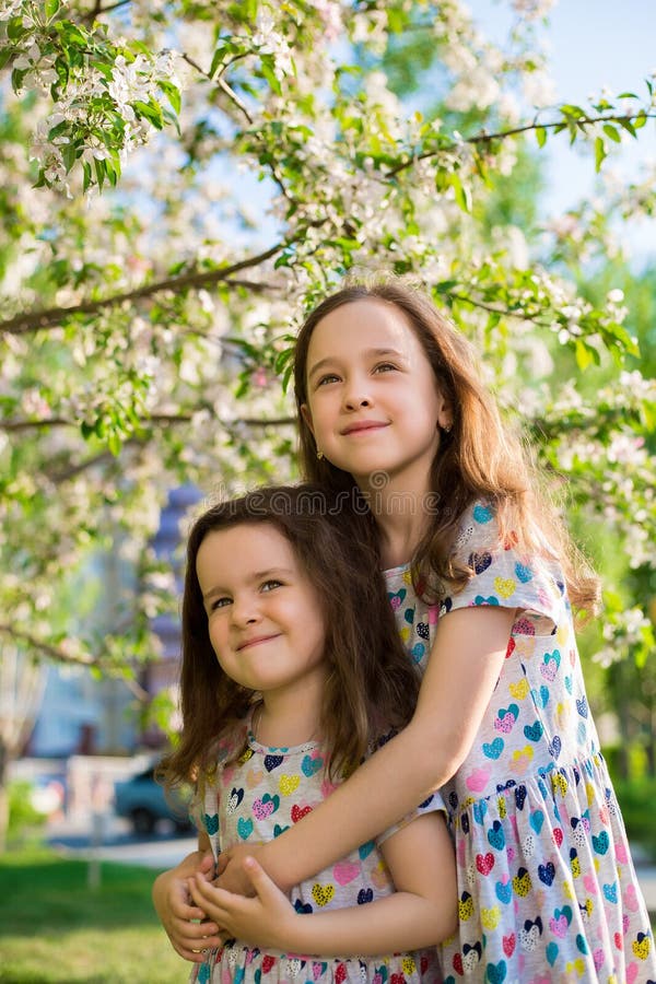 Poco muchachas felices en un paseo en una tarde del verano en la puesta del sol en el parque Hermanas fotos de archivo Poco muchachas felices en un paseo en una tarde del verano en la puesta del sol en el parque Hermanas fotos de archivo
