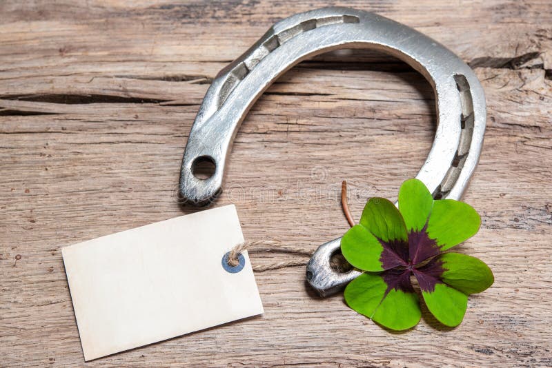 Horseshoe and four leaf clover with empty tag on old wooden. Horseshoe and four leaf clover with empty tag on old wooden