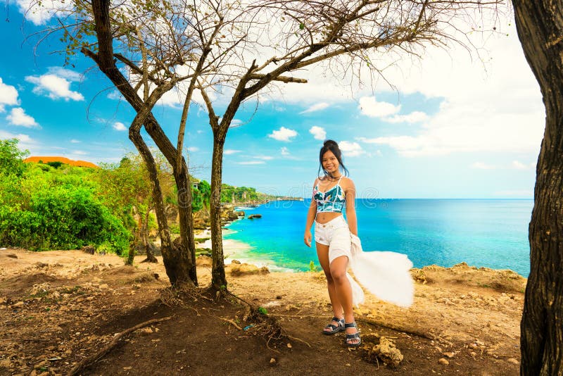 Podróżnik z podnieceniem kobieta cieszy się zadziwiającego natura krajobraz tropikalny plażowy Pantai Bali od wierzchołka halna f fotografia royalty free Podróżnik z podnieceniem kobieta cieszy się zadziwiającego natura krajobraz tropikalny plażowy Pantai Bali od wierzchołka halna f fotografia royalty free