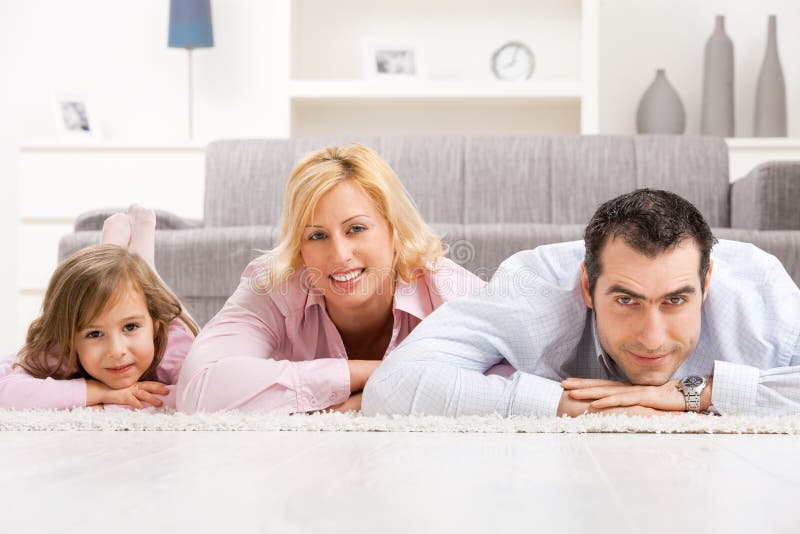 Happy couple and their daugther lying together on floor in living room. Happy couple and their daugther lying together on floor in living room.
