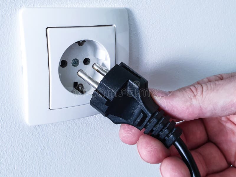 Podłączanie czarnego wtyczki zasilania elektrycznego ręką do białego plastikowego gniazda zasilania obraz stock