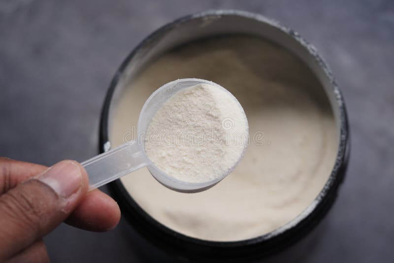 Poeder afmeten uit een container met een schep in de hand stock afbeeldingen