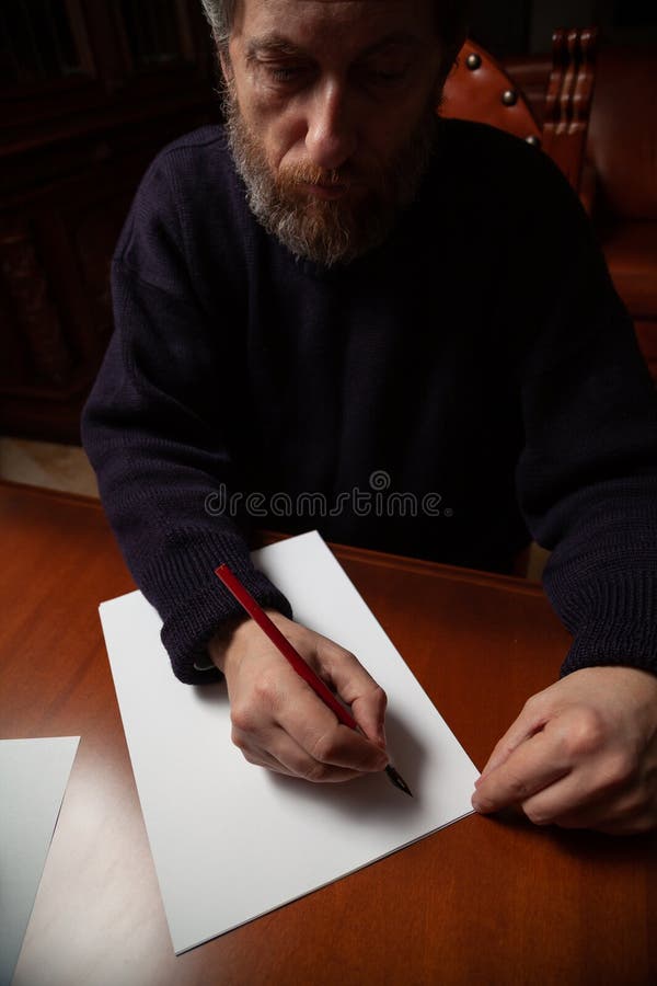 Poet with beard writes in ink on white sheet royalty free stock photo