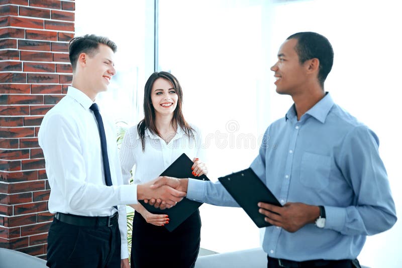 Poign?e de main de jeunes associ?s dans le bureau image libre de droits Poign?e de main de jeunes associ?s dans le bureau image libre de droits