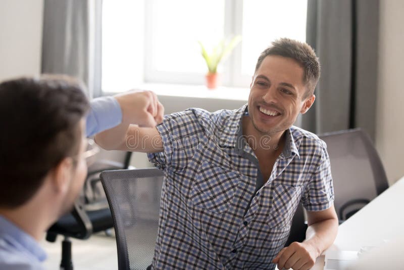 Poing de sourire d'homme se cognant avec le collègue sur le lieu de travail photographie stock libre de droits Poing de sourire d'homme se cognant avec le collègue sur le lieu de travail photographie stock libre de droits