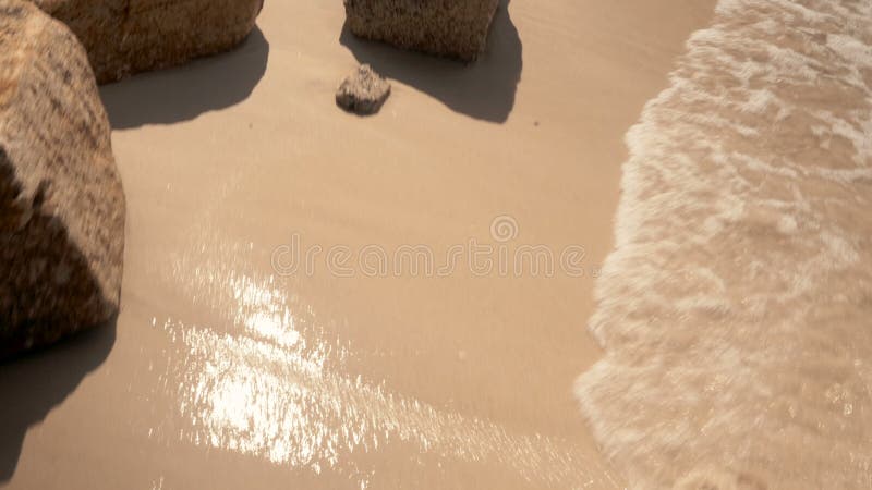 Point of view at the golden sand and rocks at sea beach. POV