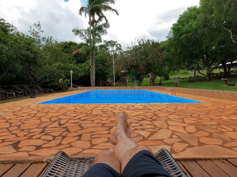 Point of view of a man lying down beside a swimming pool on a cloudy day, but very hot.