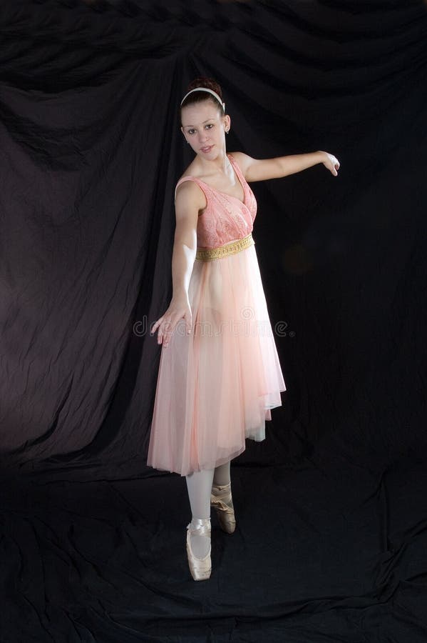 A ballerina posed on Pointe in peach colored dress