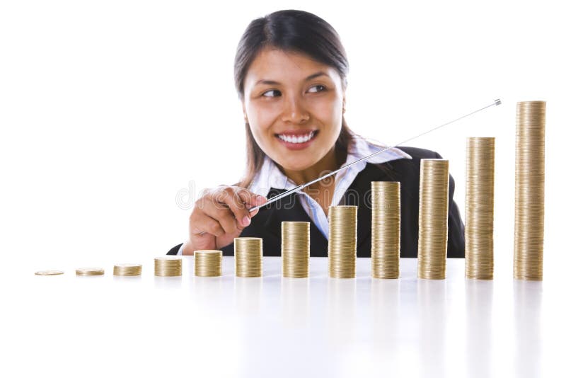 A businesswoman in background is pointing at the last bar (presenting December) from twelve coins stacks, showing growth/increasing in profit. Main focus on coin stacks. A businesswoman in background is pointing at the last bar (presenting December) from twelve coins stacks, showing growth/increasing in profit. Main focus on coin stacks.