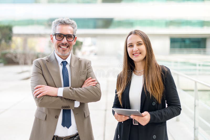 The mature businessman and his female associate stand side by side stock photography