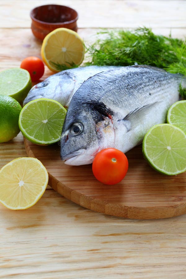 Poisson frais sur le conseil avec des citrons et des chaux images libres de droits Poisson frais sur le conseil avec des citrons et des chaux images libres de droits