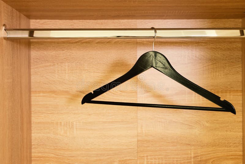 Single empty black clothing rack hanging on coathanger in closet with copy space. Single empty black clothing rack hanging on coathanger in closet with copy space