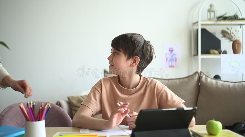 Pojke som använder en tablett för utbildning och som pratar med mamma på bordet i hemmet.. stock video
