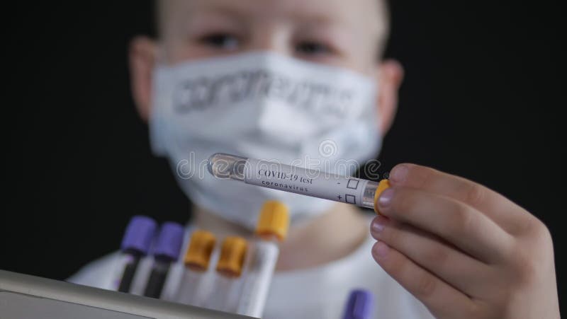 Pojke som håller i en metallväska. Ett barn undersöker ett provrör för medicinsk undersökning med ett prov för viruset.. pojken är royaltyfria foton
