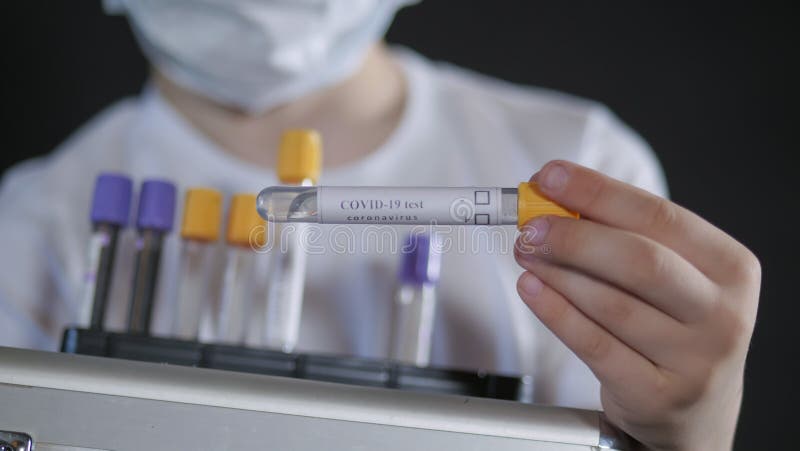 Pojke som håller i en metallväska. Ett barn undersöker ett provrör för medicinsk undersökning med ett prov för viruset.. pojken är arkivbild