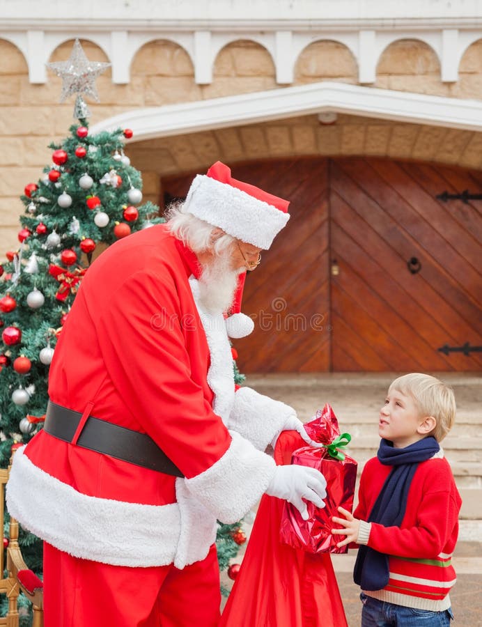 Pojke som ser Santa Claus While Taking Gift From arkivbild Pojke som ser Santa Claus While Taking Gift From arkivbild