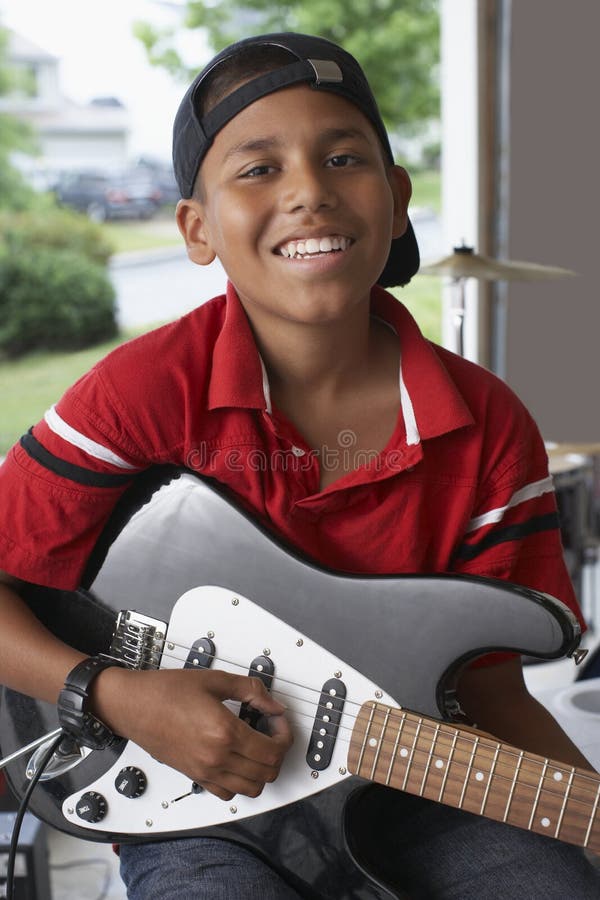 Pojke som spelar gitarren i garage arkivbild Pojke som spelar gitarren i garage arkivbild