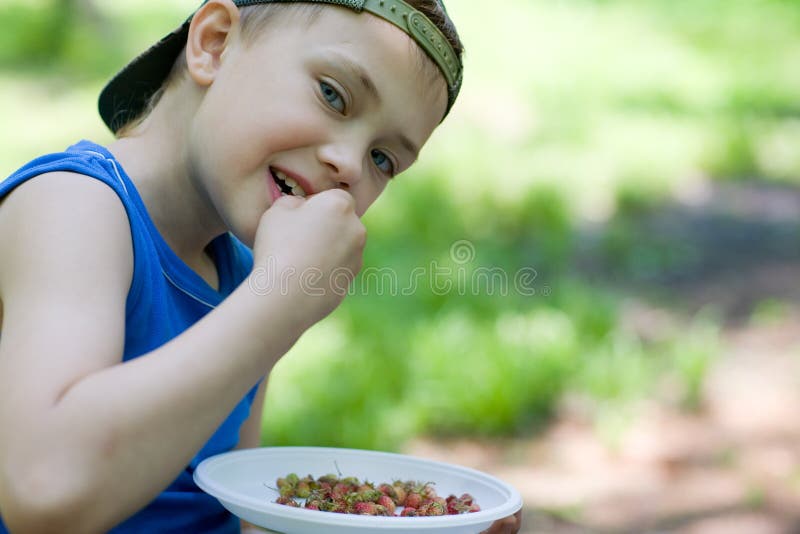 Little boy eating wild strawberries. Summer. Little boy eating wild strawberries. Summer.