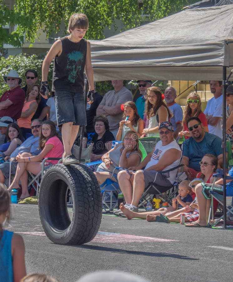 A boy walks on the top of a large rolling tire and thrills the crowd watching the Fourth of July parade in Ashland, Oregon. A boy walks on the top of a large rolling tire and thrills the crowd watching the Fourth of July parade in Ashland, Oregon.