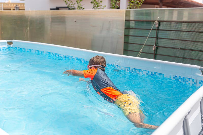 Pojken i badkläder dykning in i poolen under simning fotografering för bildbyråer