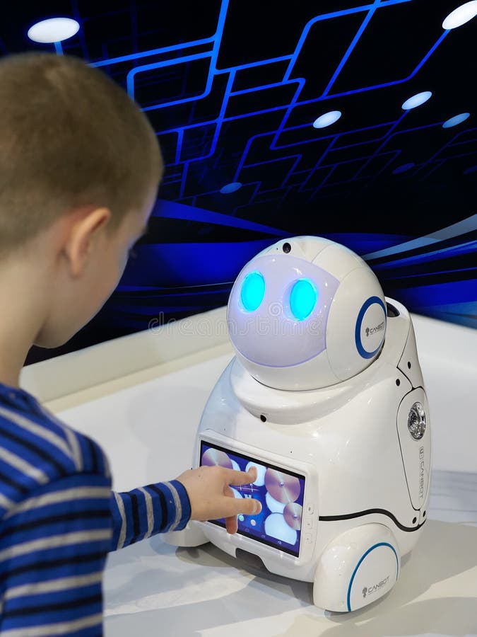 Pojken spelar med en robot på en mörk bakgrund med ett holograph royaltyfri foto Pojken spelar med en robot på en mörk bakgrund med ett holograph royaltyfri foto
