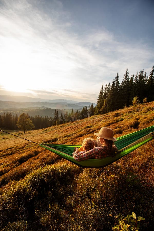 Pojkturist vilade i en hammock i bergen vid solnedgången