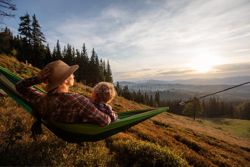Pojkturist vilade i en hammock i bergen vid solnedgången