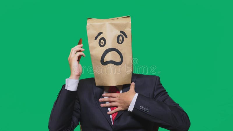 Pojęcie emocje, gesty mężczyzna z papierowymi torbami na jego głowa, z malującym emoticon, strach Opowiadać na telefonie komórkow obraz royalty free Pojęcie emocje, gesty mężczyzna z papierowymi torbami na jego głowa, z malującym emoticon, strach Opowiadać na telefonie komórkow obraz royalty free