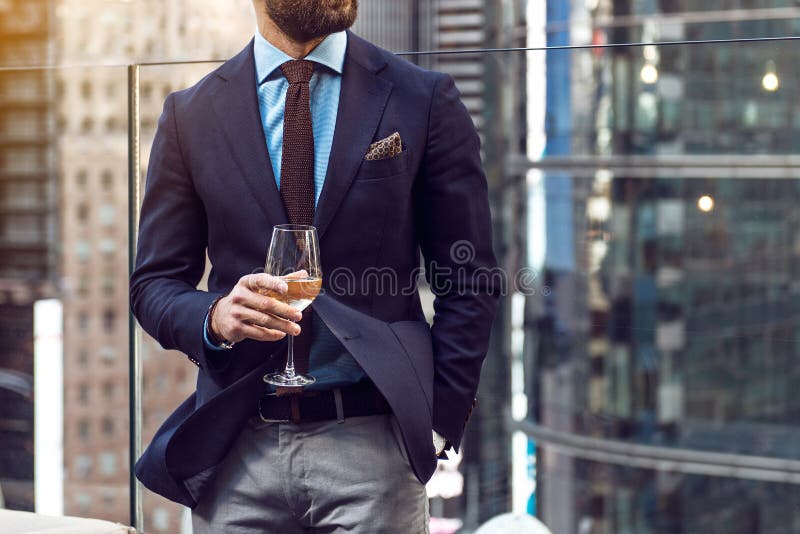 Pojęcie fotografia bogaci ludzie luksusu życia Dorosły pomyślny elegancki biznesmen jest ubranym kostium i pije wino na dachu w l
