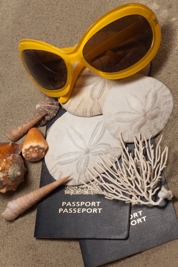 Close-Up of passports, sun glasses, sand dollars (Echinoderm), coral and shells: Beach Vacation Concept. Close-Up of passports, sun glasses, sand dollars (Echinoderm), coral and shells: Beach Vacation Concept