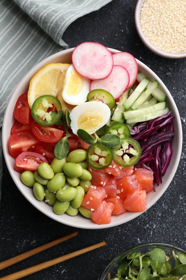 Poke Bowl with Salmon, Edamame Beans and Vegetables on Black Table