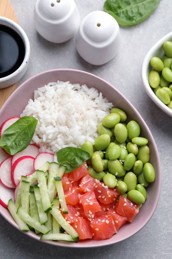 Poke Bowl with Salmon, Edamame Beans and Vegetables on Light Grey Table, Flat Lay Stock Image