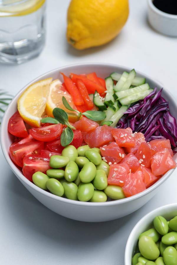 Poke Bowl with Salmon, Edamame Beans and Vegetables on White Table