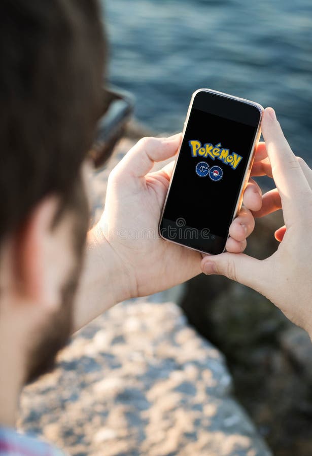 Man with sunglasses using the smartphone near the sea with pokemon go logo royalty free stock photos Man with sunglasses using the smartphone near the sea with pokemon go logo royalty free stock photos