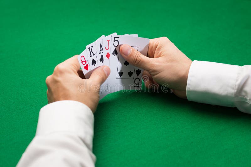 Poker player holding playing cards at casino table stock photo Poker player holding playing cards at casino table stock photo