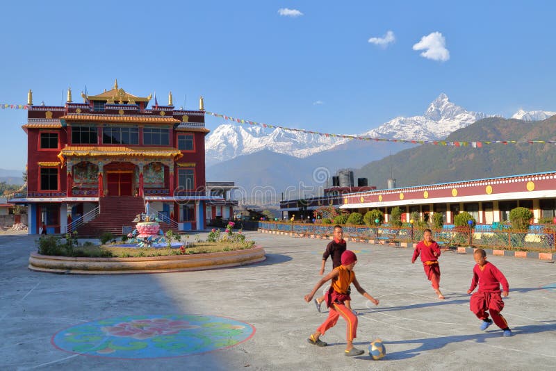 POKHARA NEPAL - JANUARI 10, 2015: Munkar som spelar fotboll i borggården av en tibetan tempel nära Pokhara Himalaya bergwi arkivbild POKHARA NEPAL - JANUARI 10, 2015: Munkar som spelar fotboll i borggården av en tibetan tempel nära Pokhara Himalaya bergwi arkivbild