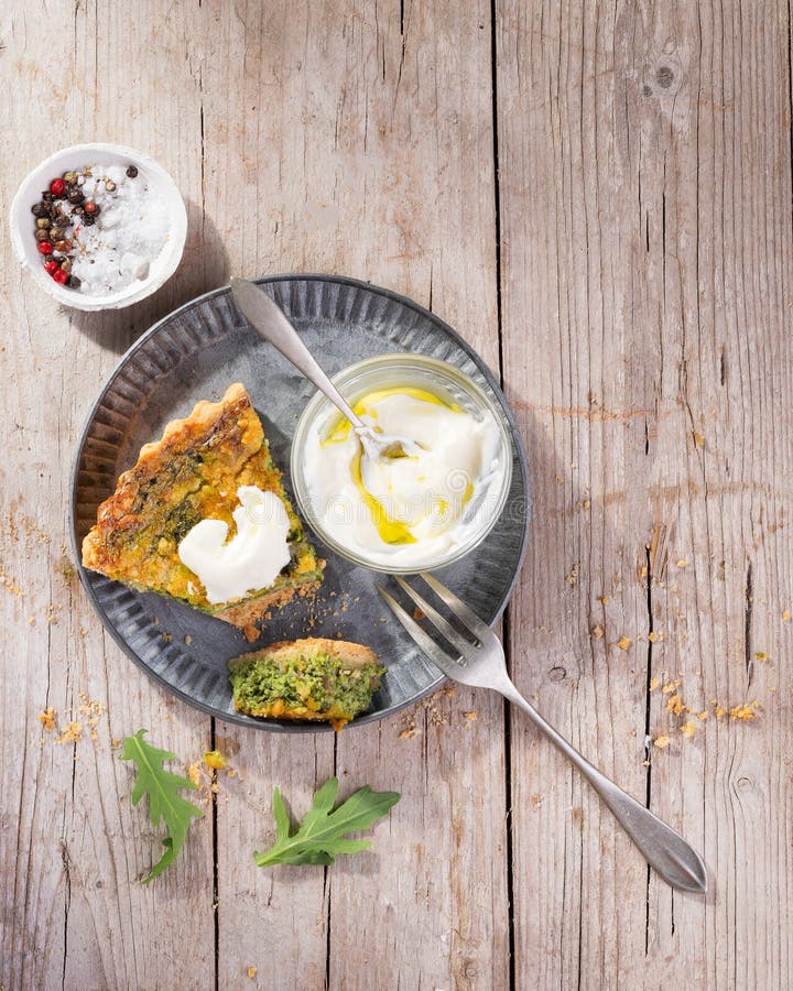 Pokrajać Quiche na talerzu z arugula, cebulą, szpinakami, mozzarellą, feta i kumberlandem na nieociosanym tle, odgórny widok, prz zdjęcie stock Pokrajać Quiche na talerzu z arugula, cebulą, szpinakami, mozzarellą, feta i kumberlandem na nieociosanym tle, odgórny widok, prz zdjęcie stock