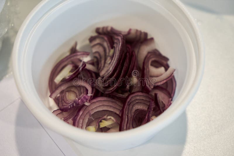 Pokrojeni świezi cebulkowi pierścionki w białym pucharze na kuchennym stole, w górę obraz royalty free Pokrojeni świezi cebulkowi pierścionki w białym pucharze na kuchennym stole, w górę obraz royalty free