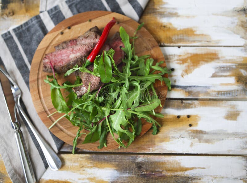 Pokrojony średni rzadki piec na grillu wołowina stek Ribeye z rakietową sałatką o obraz stock Pokrojony średni rzadki piec na grillu wołowina stek Ribeye z rakietową sałatką o obraz stock