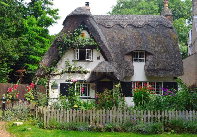 Houghton, Cambridgeshire, England - July 20, 2016: Thatched cottage with white walls and colourful garden. Houghton, Cambridgeshire, England - July 20, 2016: Thatched cottage with white walls and colourful garden.