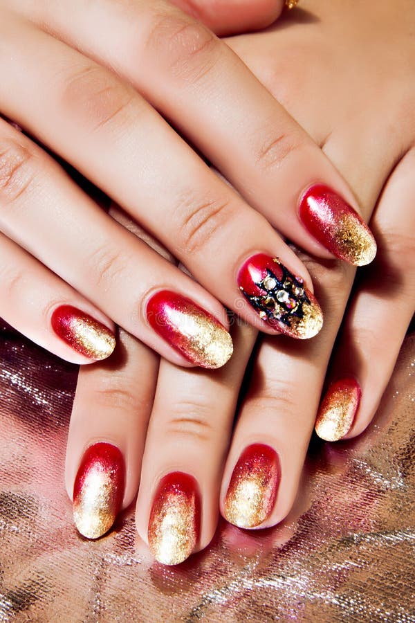 Close Up of Female Hands Wearing Bright Red and Gold Polish on Nails. Close Up of Female Hands Wearing Bright Red and Gold Polish on Nails