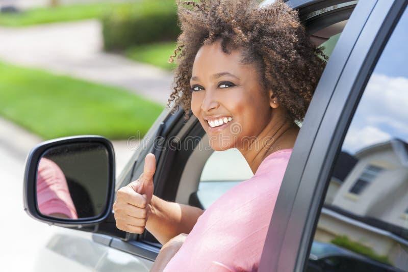 Polegares afro-americanos da mulher da menina que conduzem acima o carro
