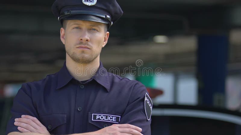 Policial respeitável que olha para a câmara, policia os distritos da cidade